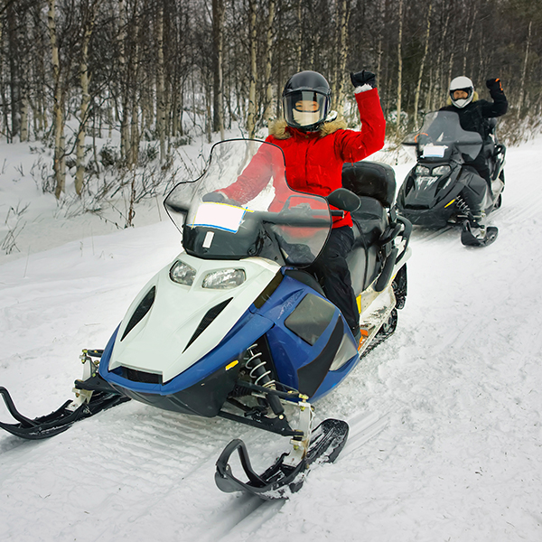 two people riding snowmobiles